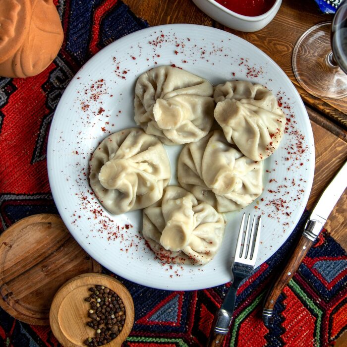 top view of traditional georgian khinkaliwith sumakh and spicy sauce on a white plate